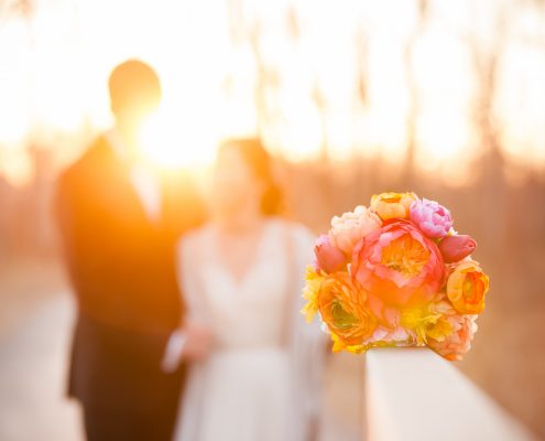 Newlyweds with the bride's gorgeous bouquet enjoying sunset together